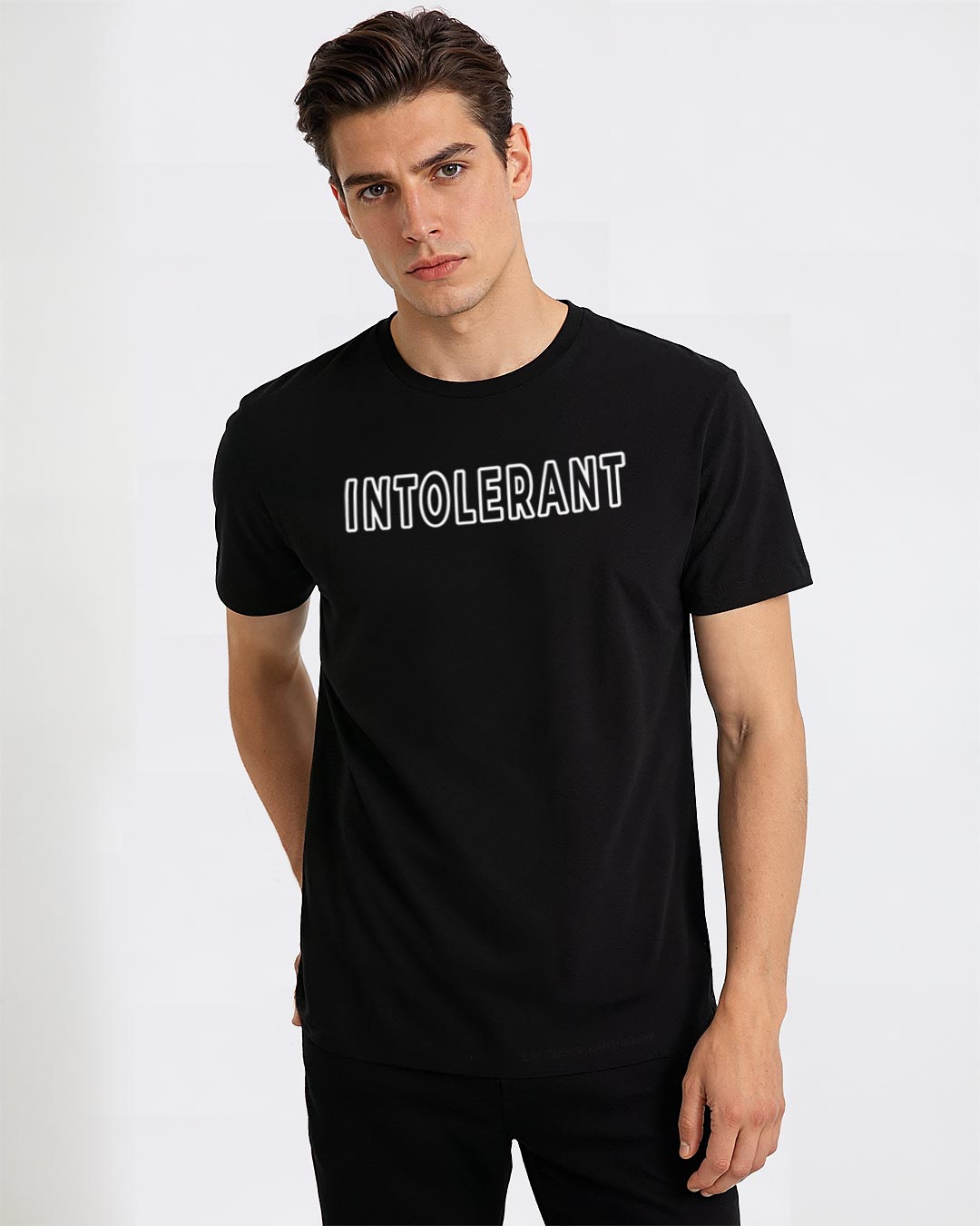 Junger Mann präsentiert das schwarze INTOLERANT Classic T-Shirt in souveräner Pose vor hellem Hintergrund – klarer, ordentlicher Look mit starkem Kontrast.