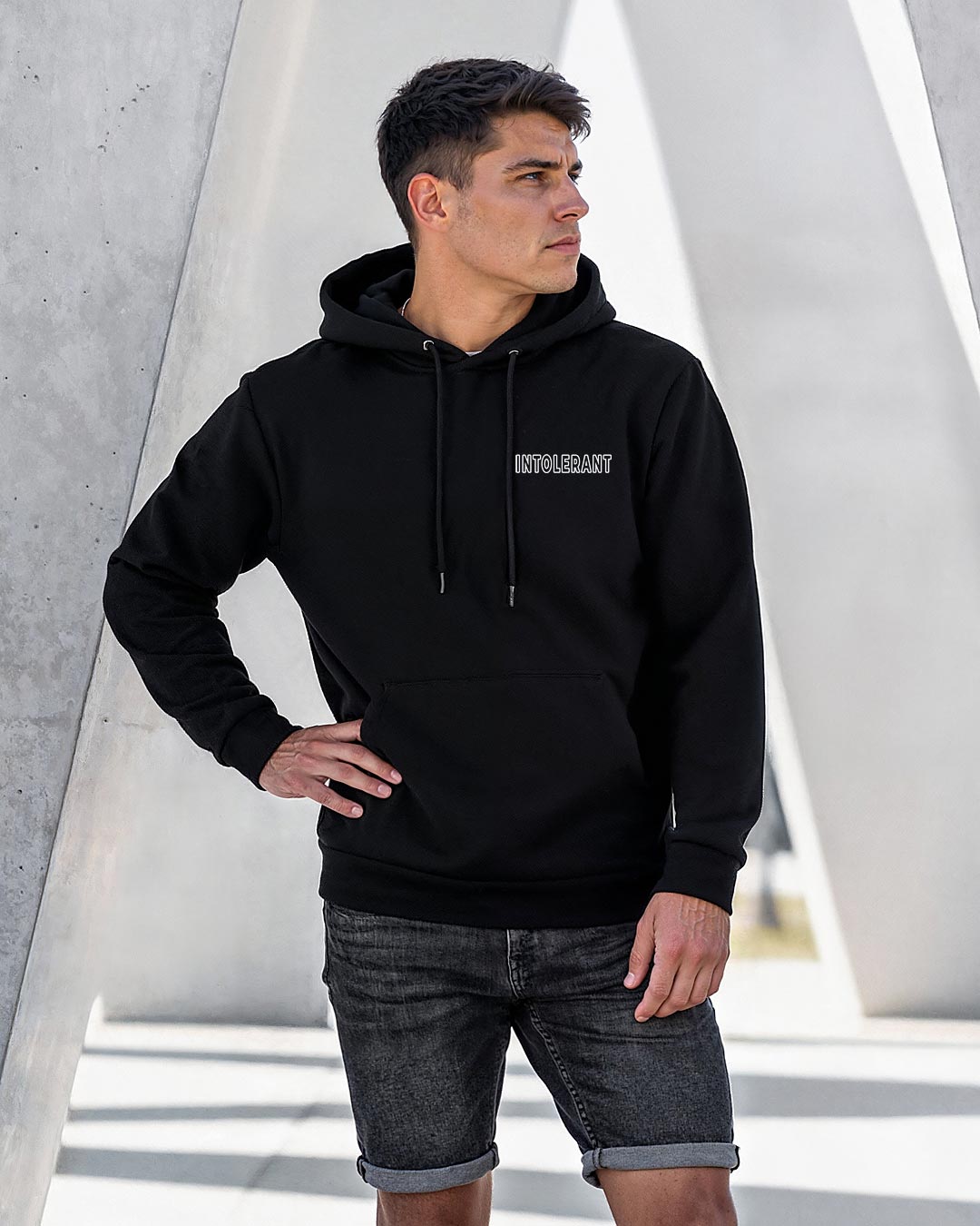 Lifestyle-Aufnahme eines jungen Mannes im schwarzen INTOLERANT Minimal Hoodie – verkörpert Eleganz und Stil durch dezente Details.