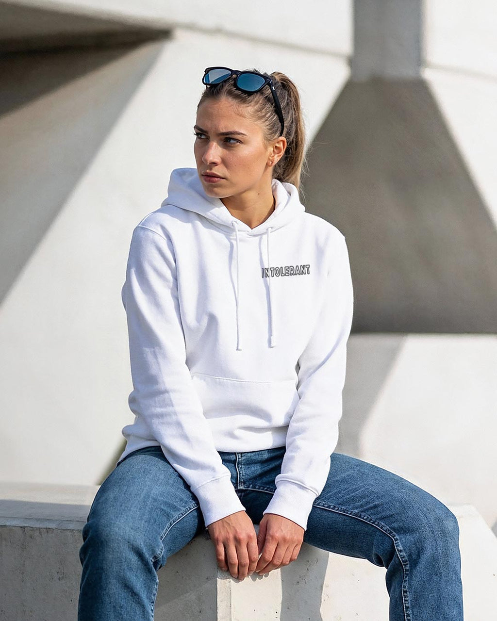 Lifestyle-Außenaufnahme im weißem INTOLERANT Minimal Hoodie – verkörpert Rückgrat und Stil durch dezente Klarheit.