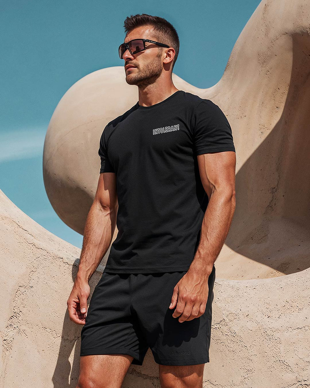 Außenaufnahme eines jungen muskulösen Mannes im schwarzen INTOLERANT Minimal T-Shirt – zeitlose Ästhetik trifft bestechende Schönheit.