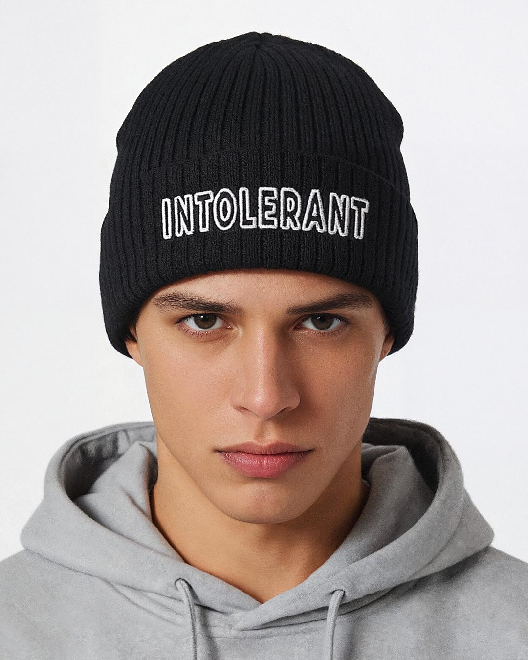Junger Mann mit der schwarzen INTOLERANT Statement Beanie – winterlicher, konservativer Look mit Fokus auf den hochwertigen Front-Stick.