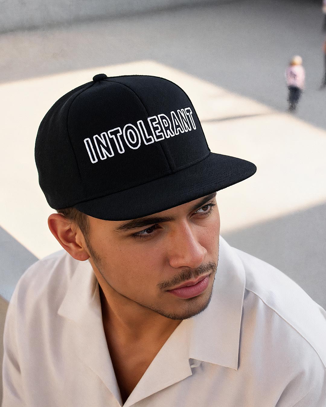 Lifestyle-Ansicht der schwarzen INTOLERANT Snapback Cap – ein elegant gekleideter junger Mann strahlt selbstbewusste Klarheit aus.